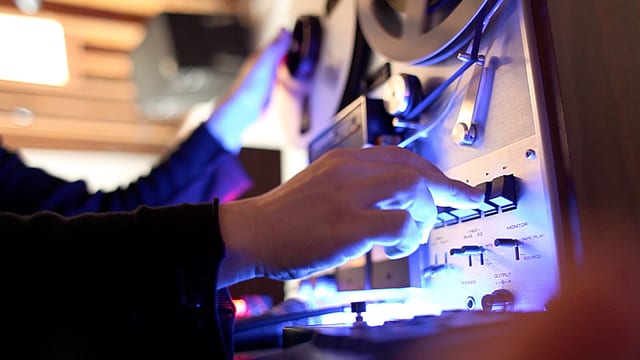 Eine Hand bedient eine alte Bandmaschine Eine Hand bedient eine alte Bandmaschine