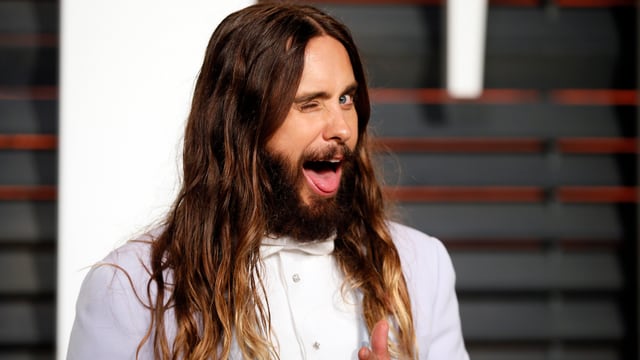 Jared Leto mit langer Wallemähne in Kamera grinsend. Jared Leto mit langer Wallemähne in Kamera grinsend.