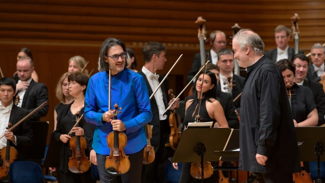 Geiger und Dirigent vor Orchester Geiger und Dirigent vor Orchester