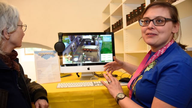 Patricia Pollinger erklärt einer Frau, wie ein Game funktioniert. Patricia Pollinger erklärt einer Frau, wie ein Game funktioniert.