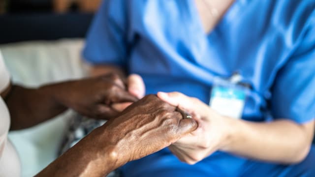 eine Pflegerin hält die Hand einer Patientin eine Pflegerin hält die Hand einer Patientin