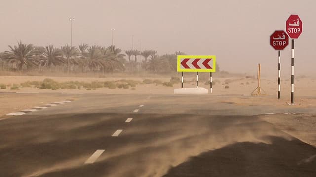 Eine Strasse in der Wüste, Sand wird vom starken Wind umhergeweht. Eine Strasse in der Wüste, Sand wird vom starken Wind umhergeweht.