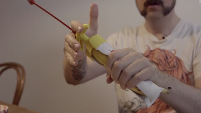 Guido spannt eine Banane in eine spezielle Halterung und hölt sie aus Guido spannt eine Banane in eine spezielle Halterung und hölt sie aus