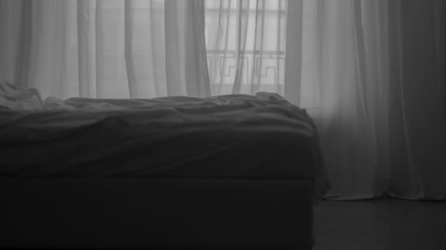Bett mit weissem Bezug und weissen Vorhängen vor dem Fenster Bett mit weissem Bezug und weissen Vorhängen vor dem Fenster