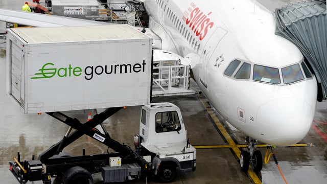 Aus einem zur Flugzeugtür hochgefahrenen Container mit der Aufschrift "Gategourmet" wird Essen in ein am Gate geparktes Swiss-Flugzeug eingeladen. Aus einem zur Flugzeugtür hochgefahrenen Container mit der Aufschrift "Gategourmet" wird Essen in ein am Gate geparktes Swiss-Flugzeug eingeladen.