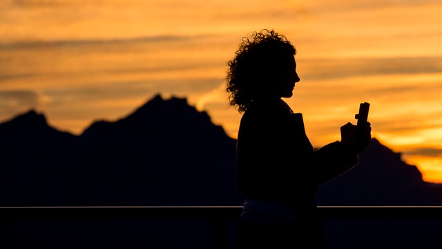 Frau macht Selfie vor Bergkulisse Frau macht Selfie vor Bergkulisse