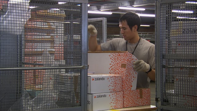 Zalando-Lagerarbeiter stapelt Pakete Zalando-Lagerarbeiter stapelt Pakete