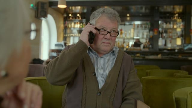 Ein älterer Mann telefoniert mit dem Handy. Er trägt eine grosse schwarze Brille und schaut skeptisch. Ein älterer Mann telefoniert mit dem Handy. Er trägt eine grosse schwarze Brille und schaut skeptisch.