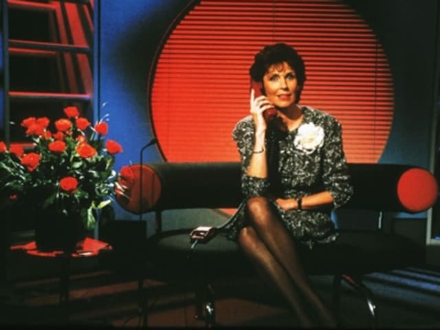 Erika Berger sitzt auf einem Sofa und hält einen Telefonhörer in der Hand. Erika Berger sitzt auf einem Sofa und hält einen Telefonhörer in der Hand.