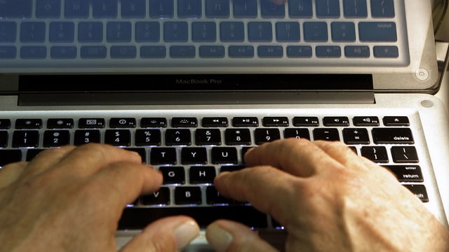 Eine Person tippt auf einem Laptop. Eine Person tippt auf einem Laptop.