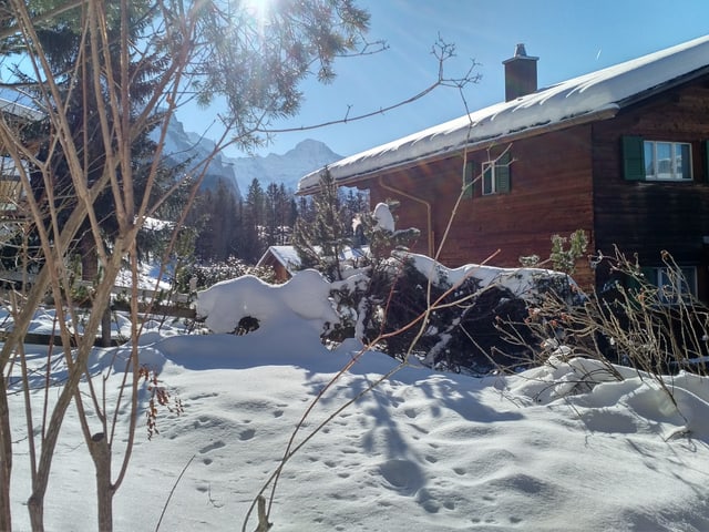 Chalet im Sonnenschein, im Hintergrund Berge