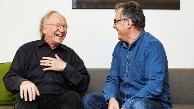 Zwei Männer unterhalten sich und lachen Zwei Männer unterhalten sich und lachen
