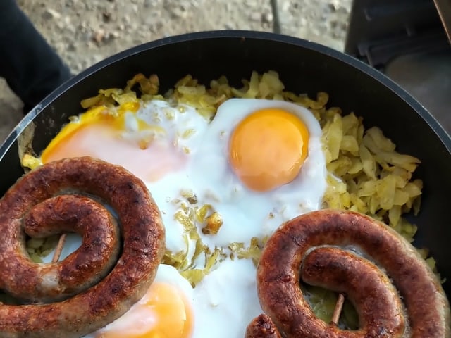 Grillschneck, Rösti und Spiegeleier auf einer Pfanne- Grillschneck, Rösti und Spiegeleier auf einer Pfanne-