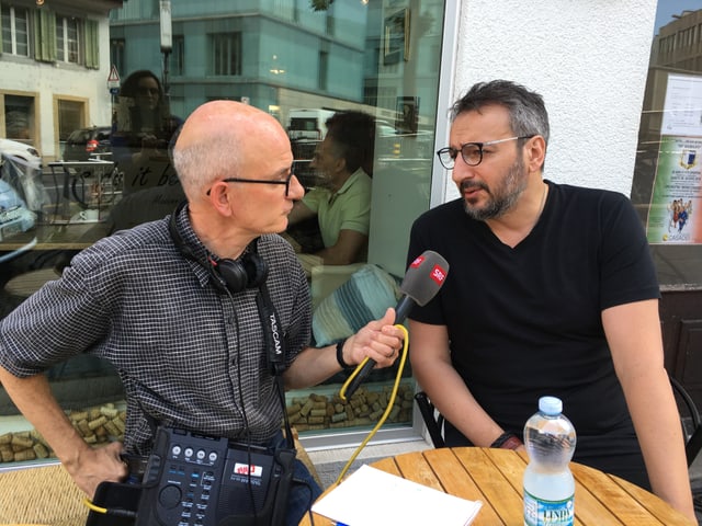 Zwei Männer unterhalten sich an einem Bistro-Tisch Zwei Männer unterhalten sich an einem Bistro-Tisch