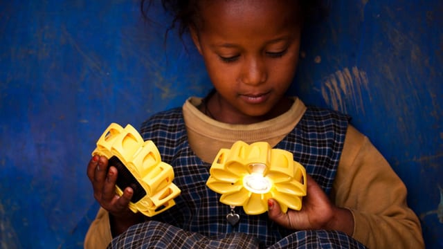 Ein Mädchen hält die Sonnen-LED-Lampe.