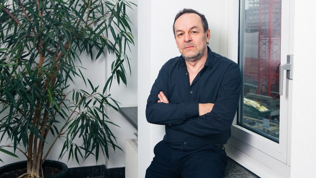 Ein Mann sitzt auf einer Fensterbank. Ein Mann sitzt auf einer Fensterbank.