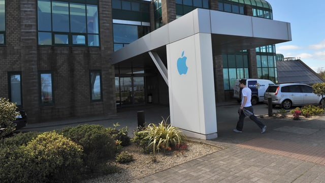 Ein Mann geht in ein Unternehmensgebäude von Apple in Irland. Ein Mann geht in ein Unternehmensgebäude von Apple in Irland.