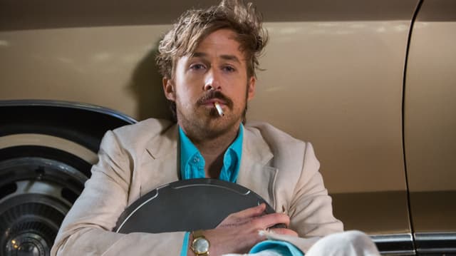 Ryan Gosling völlig zerzaust am Boden: mit einer Filmrolle in der Hand und einer Zigarette im Mund.