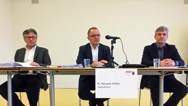 Drei Männer sitzen an einem Tisch Drei Männer sitzen an einem Tisch