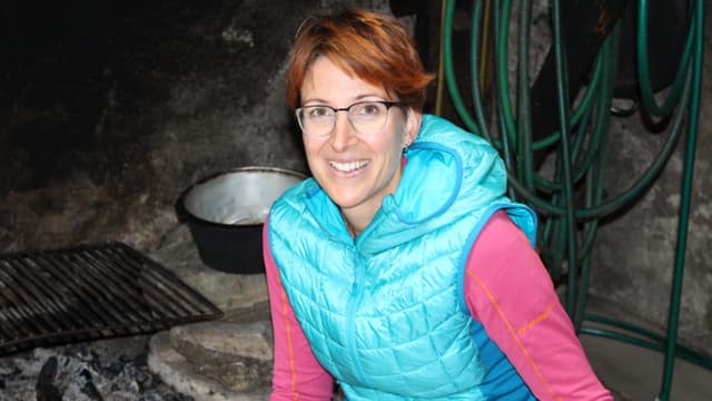 Eine Frau sitzt vor einer Feuerstelle am Boden. Eine Frau sitzt vor einer Feuerstelle am Boden.