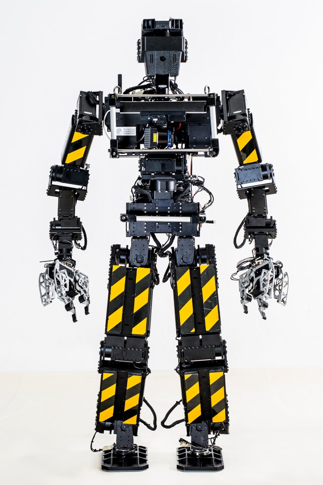 Ein menschenähnlicher Roboter mit Armen und Beinen, auf denen gelbe Streifen angebracht sind. Ein menschenähnlicher Roboter mit Armen und Beinen, auf denen gelbe Streifen angebracht sind.