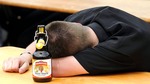 Betrunkener schläft auf einem Festtisch. Neben ihm steht eine Flasche saurer Most. Betrunkener schläft auf einem Festtisch. Neben ihm steht eine Flasche saurer Most.