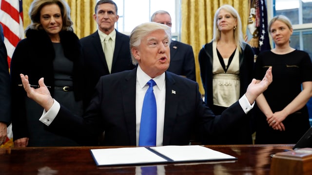 Donald Trump sitzt an einem Tisch. Donald Trump sitzt an einem Tisch.