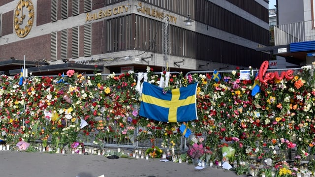 Zahlreiche Blumen und Kerzen wurden an einem Gitter angebracht. Zahlreiche Blumen und Kerzen wurden an einem Gitter angebracht.