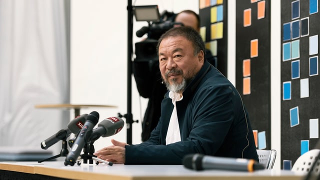 Ai Weiwei im Porträt an einem Pult. Ai Weiwei im Porträt an einem Pult.