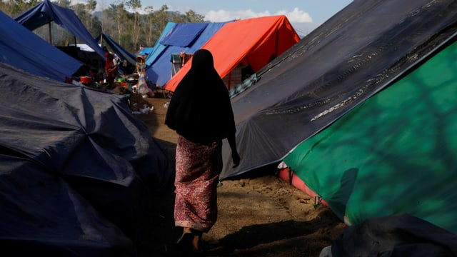 Frau von hinten in einem improvisierten Zeltlager auf Lombok. Frau von hinten in einem improvisierten Zeltlager auf Lombok.