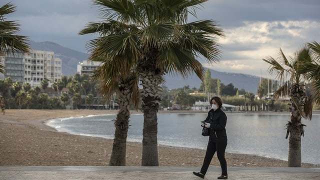 Frau mit Maske an Strandpromenade Frau mit Maske an Strandpromenade