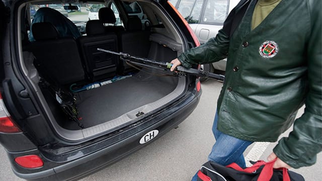 Mann nimmt Sturmgewehr aus Kofferraum. Mann nimmt Sturmgewehr aus Kofferraum.