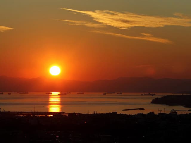 Zu sehen ist ein Sonnenuntergang an einem Hafen.