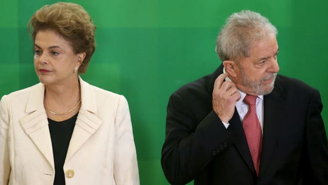 Rousseff und Lula stehen nebeneinander und blicken in unterschiedliche Richtungen, Lula kratzt sich am Ohr. Rousseff und Lula stehen nebeneinander und blicken in unterschiedliche Richtungen, Lula kratzt sich am Ohr.
