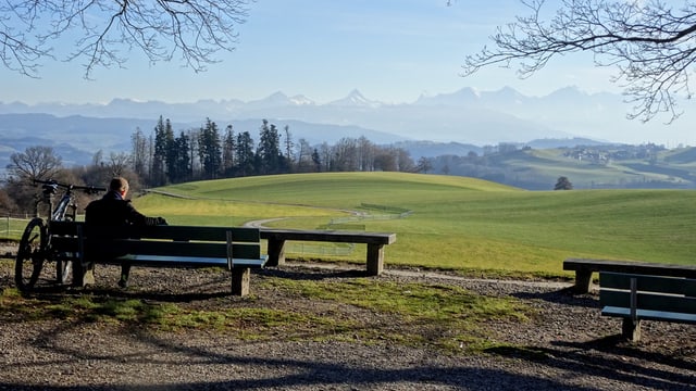 Ein Wanderer geniesst den Ausblick vom Gurten zu den aperen Berner Alpen. Ein Wanderer geniesst den Ausblick vom Gurten zu den aperen Berner Alpen.