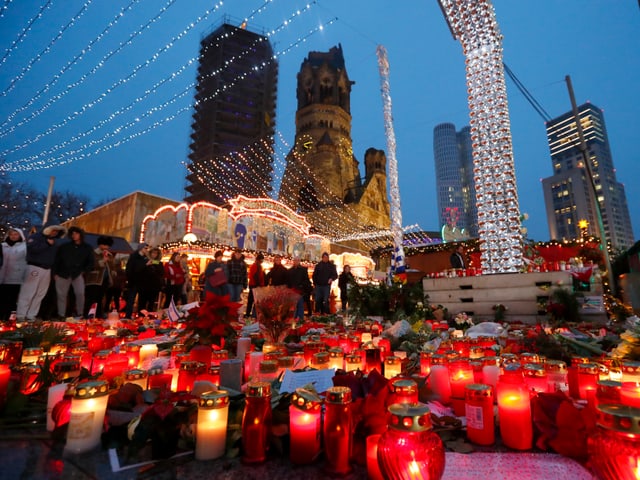 Kerzen, dahinter der Weihnachtsmarkt und Hochhäuser