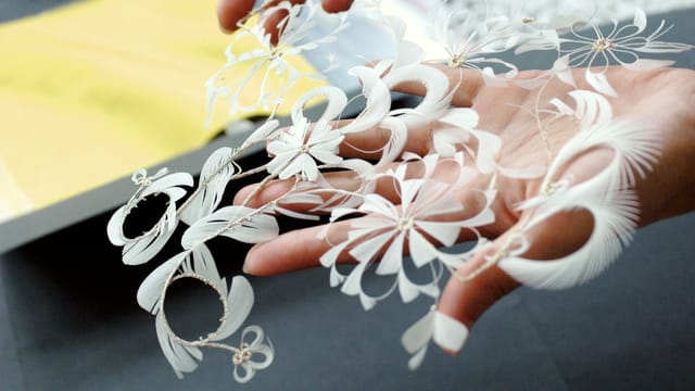 Eine Frau hält ein filigranes Textil in der Hand. Eine Frau hält ein filigranes Textil in der Hand.