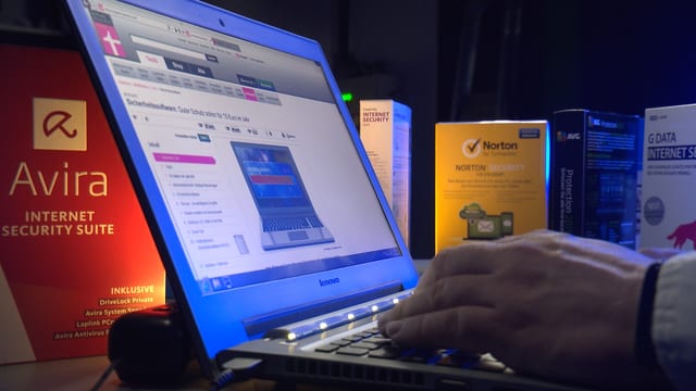 Ein Mann arbeitet an einem Laptop, darum herum stehen verschiedene Antivirenschutz-Programme. Ein Mann arbeitet an einem Laptop, darum herum stehen verschiedene Antivirenschutz-Programme.