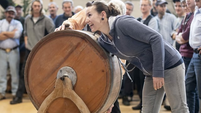 Eine Frau zieht ein Los aus dem alten, hölzernen Butterfass. Eine Frau zieht ein Los aus dem alten, hölzernen Butterfass.