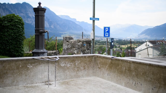 Trockener, leerer Brunnen. Im Hintergrund Blick auf das weite Churer Rheintal. Trockener, leerer Brunnen. Im Hintergrund Blick auf das weite Churer Rheintal.