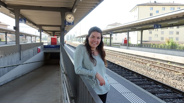 Junge Frau steht auf dem Perron am Bahnhof und lächelt freundlich in die Kamera Junge Frau steht auf dem Perron am Bahnhof und lächelt freundlich in die Kamera