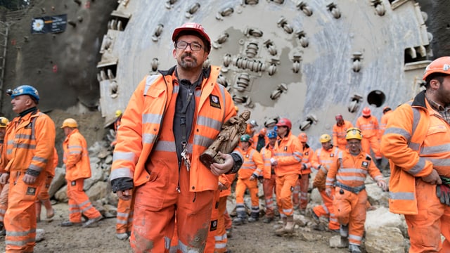 Bauarbeiter in orangen Kleidern vor einer Tunnelbohrmaschine. Bauarbeiter in orangen Kleidern vor einer Tunnelbohrmaschine.