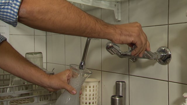 Wirt füllt Karaffe mit Wasser aus Hahn Wirt füllt Karaffe mit Wasser aus Hahn