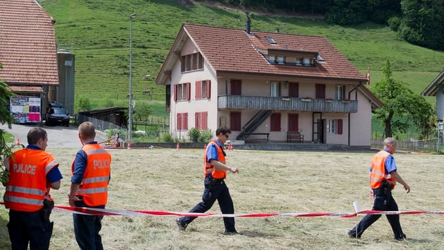 Blick über eine Wiese mit vier Polizisten. Blick über eine Wiese mit vier Polizisten.