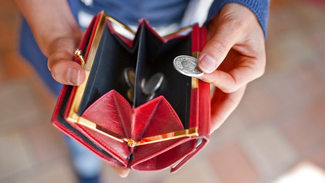 Ein rotes Portemonnaie mit Münzen darin. Ein rotes Portemonnaie mit Münzen darin.