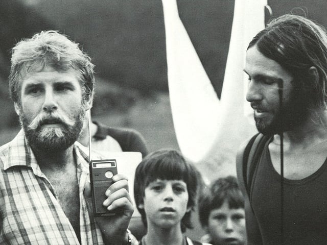 Schwarz-Weiss Foto von Markus Liechti und Kurt Saurer, die von ein paar Buben aufmerksam beobachtet werden. Schwarz-Weiss Foto von Markus Liechti und Kurt Saurer, die von ein paar Buben aufmerksam beobachtet werden.