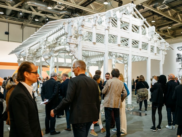 Menschen auf einer Kunstmesse vor einem weissen Haus ohne Wände. Menschen auf einer Kunstmesse vor einem weissen Haus ohne Wände.
