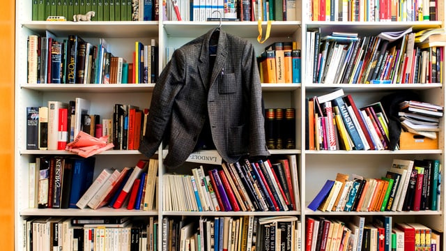 Jacket hängt an Kleiderhaken vor Bücherregal
