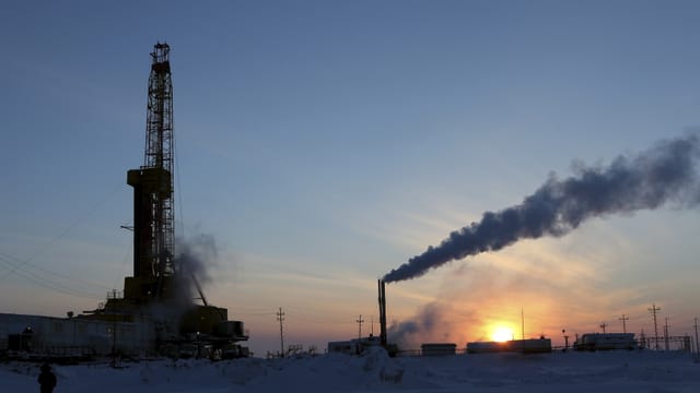 Ölbohrturm udn rauchender Schlot im Schnee bei Sonnenaufgang. Ölbohrturm udn rauchender Schlot im Schnee bei Sonnenaufgang.