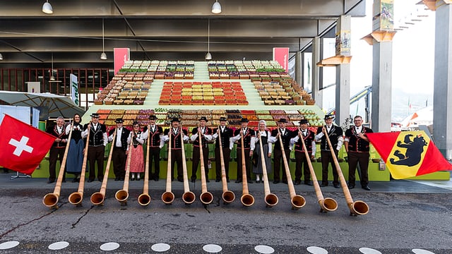 Menschen in Trachten, mit Fahne und Alphorn stehen auf dem Olma-Areal. Menschen in Trachten, mit Fahne und Alphorn stehen auf dem Olma-Areal.